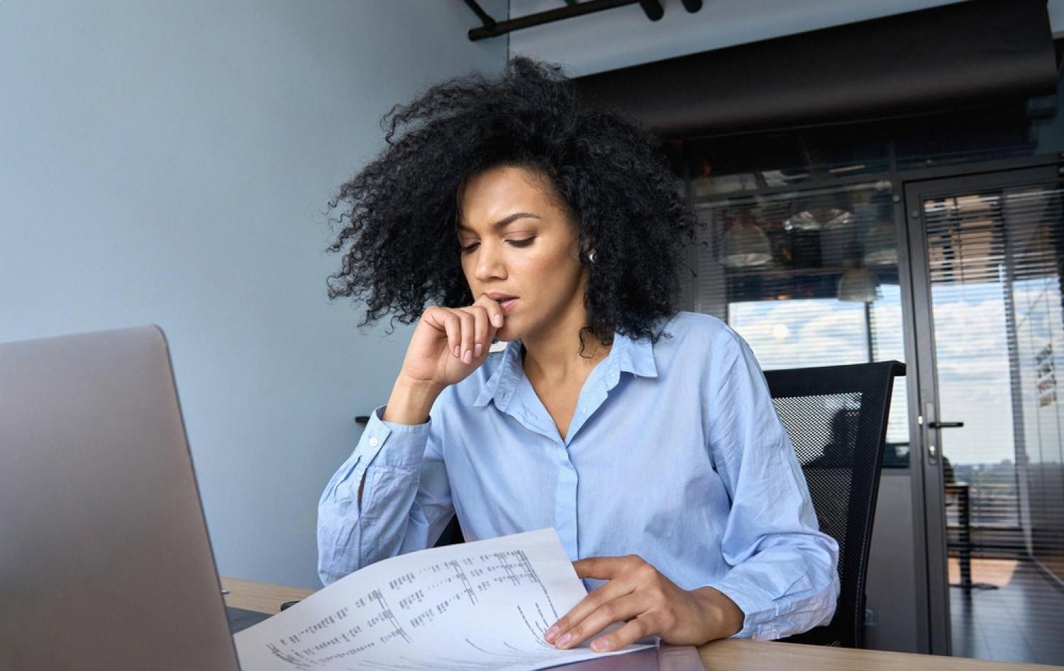 Woman in Dubai office reviewing financial statements and thinking about delayed investment decisions